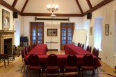 Une grande table en U est placée au centre d'une pièce lumineuse avec un haut plafond et un foyer en pierre.