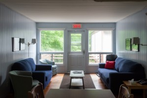 L'aire de repos des chalets de la Réserve naturelle Gault. Deux sofas bleues se font face près de grandes fenêtres donnant sur la forêt.