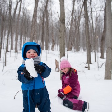 Two young kids playing in the snow.