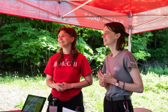 Both smiling, Olivia (left) and Morgane (right) stand side by side at an educational kiosk.