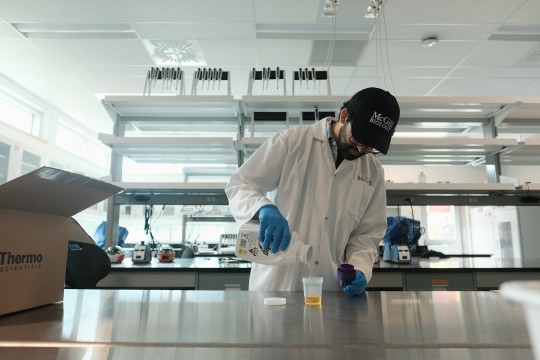 A researcher measures a quantity of herbicide for his experiment in a laboratory.