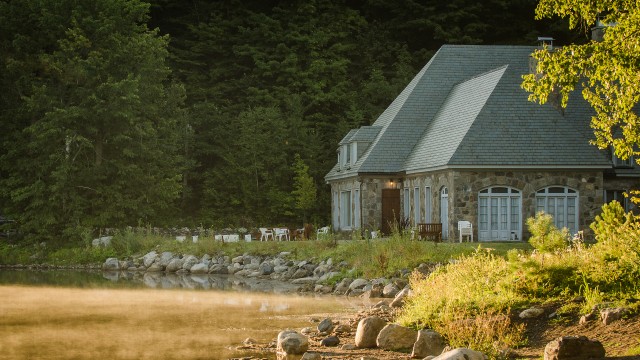 A stone house by a lake in summer.