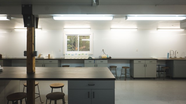 A laboratory interior featuring lab benches and stools