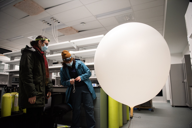 Two researchers examine a large white balloon in a laboratory