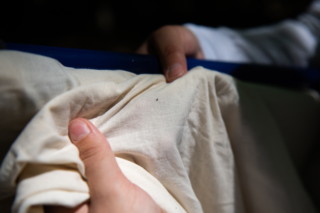 A young woman inspects a white fabric from up close.