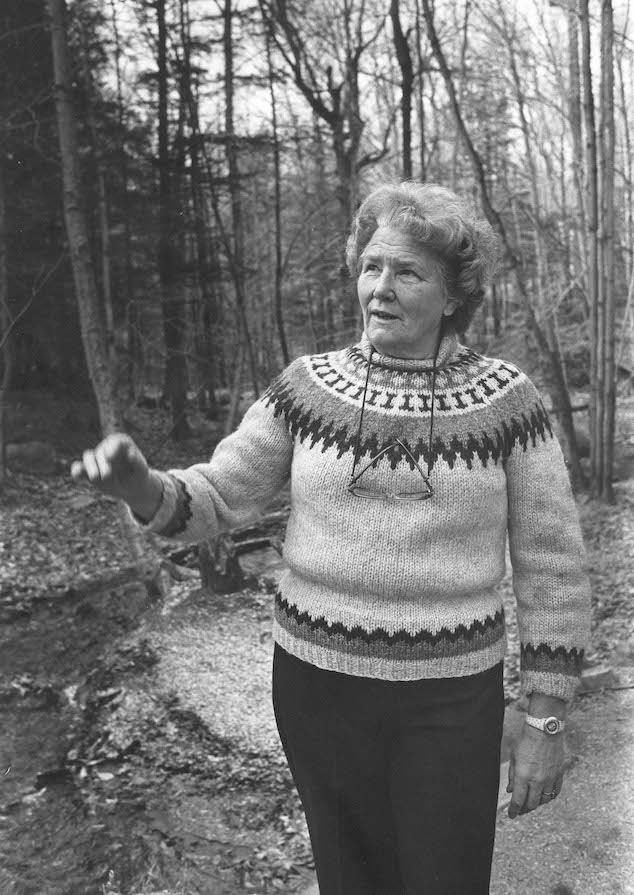 Alice Johannsen, a woman, is standing in a forested path
