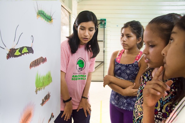 An educator shows caterpillar drawings to a group of kids