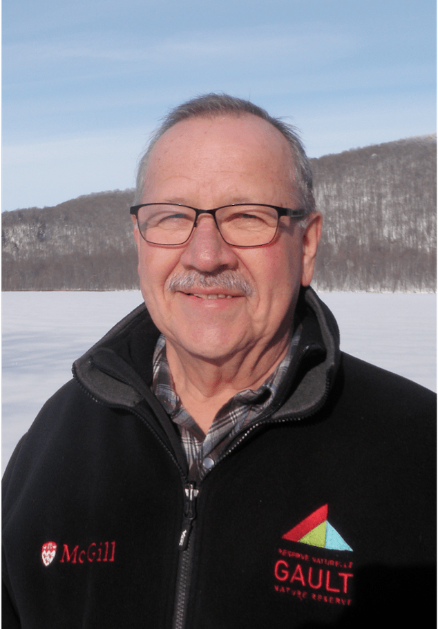 Portrait d'un homme portant un uniforme avec le logo de McGill et de la Réserve naturelle Gault devant un lac glacé