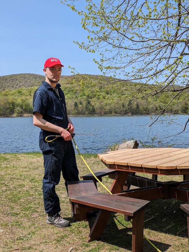 An intern power-washes a picnic table.