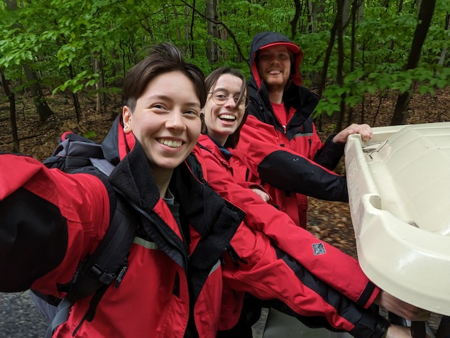 Three interns ride on the back of a golf cart. 